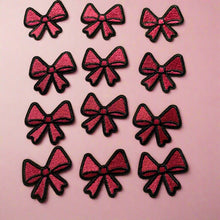 Load image into Gallery viewer, Twelve pink and black embroidered mini bow patches arranged on pink background showing size and design detail.