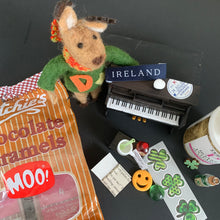 Load image into Gallery viewer, Dessie the reindeer with the Ireland piano decal, basket of potatoes, and shamrock decals on a dark surface