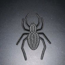 Load image into Gallery viewer, A black embroidered spider patch shown from above on a dark gray background.
