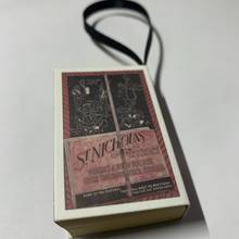 Load image into Gallery viewer, Bookworm's Holiday Ornament. The ornament is an open book; there's space to write a special message or add a personal touch. It's a perfect addition to your holiday decor, especially for book lovers and literary enthusiasts.
