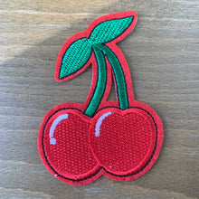 Load image into Gallery viewer, Close-up of embroidered red cherry iron-on patch, pictured on a wood table.