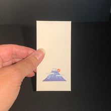 Load image into Gallery viewer, A hand holding a small cream-colored rectangular mini envelope featuring a minimalist blue and orange mt. fuji illustration with a sun, set against a dark background.