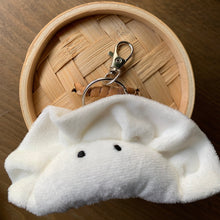 Load image into Gallery viewer, Plush Wonton dumpling keychain bag charm. White fleece with black cartoon eyes. shown with bamboo steam basket on wood table.