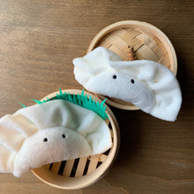 Load image into Gallery viewer, Plush Wonton dumpling keychain bag charm. White fleece with black cartoon eyes. shown with bamboo steam basket on wood table.