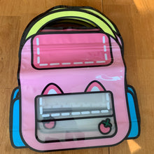Load image into Gallery viewer, A pink, cartoon-style vinyl bag shaped like a backpack with cat ears and a small strawberry graphic, displayed on a wooden surface.