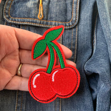 Load image into Gallery viewer, Close-up of embroidered red cherry iron-on patch, pictured against a denim jacket.