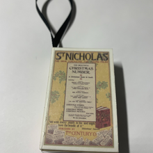 Load image into Gallery viewer, A close-up view of the Bookworm's Holiday Ornament. The ornament is an open book; there's space to write a special message or add a personal touch. It's a perfect addition to your holiday decor, especially for book lovers and literary enthusiasts.