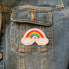 Load image into Gallery viewer, Three-pack 2 x1 inch embroidered iron-on patches with classic rainbows and two clouds, featuring a cute 80’s style. Ideal for customizing jackets, bags, shoes, and children's clothing. Shown on wood table.