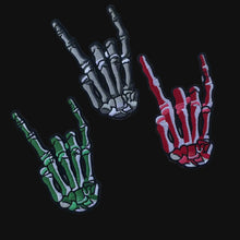 Load image into Gallery viewer, Set of three embroidered iron-on skeleton hand patches—gray, red, and green—each making the rock-on / I-love-you sign on a neutral background.
