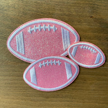 Load image into Gallery viewer, 3 pack embroidered glitter football iron-on patch set for cheer, football fans. Displayed on wood table.