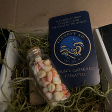 Load image into Gallery viewer, A curated gift box contents shot featuring a small glass vial filled with tea-stained foam teeth with red roots resting in green moss, next to a dark blue card labeled 'Element Ah' and 'Found Gathered, Curated.'
