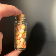 Load image into Gallery viewer, A miniature glass vial with a cork stopper, held by a hand. The vial is filled with small, hand-painted, realistic human teeth in an aged and bloody finish, set against a dark gray background.
