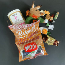 Load image into Gallery viewer, Packaged chocolate caramels with a toy deer and other small items on a dark surface

