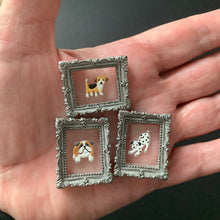 Load image into Gallery viewer, Three small square jewelry pieces with ornate silver frames and dog illustrations, held in a person's hand against a dark background.
