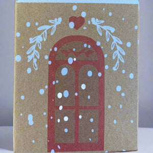 Close-up of paper cottage house box with window, snow, heart, and evergreen bough details.