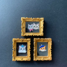 Load image into Gallery viewer, Three small framed cat portraits with ornate gold frames and black backgrounds, arranged on a dark gray surface.
