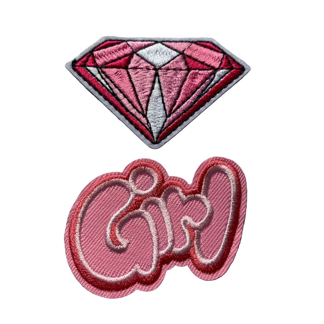 Two embroidered patches on a gray background, one shaped like a diamond and pink emboidered word girl in balloon script.