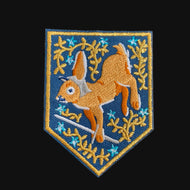 Embroidered heraldic patch of a rabbit running through foliage on a dark background
