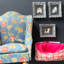 Load image into Gallery viewer, A dollhouse armchair in a blue floral print, alongside three small framed dog illustrations and a pink gingham dog bed, all arranged on a dark background.
