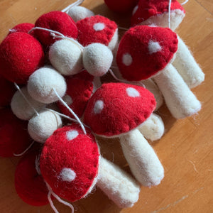 Close-up of a 72-inch garland featuring needle-felted red and white mushroom shapes and felt balls, made with wool and cotton fibers.