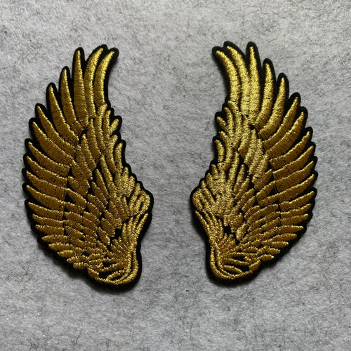 Two gold embroidered wing patches on a gray background
