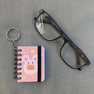 Tiny but mighty! Shown with glasses. These adorable keychain notebooks are your go-to for on-the-go lists. Never miss a detail with their compact design, measuring just 2.6" x 1.8". 