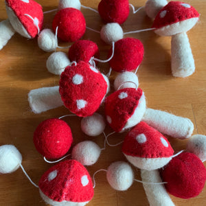 Close-up of a 72-inch garland featuring needle-felted red and white mushroom shapes and felt balls, made with wool and cotton fibers.