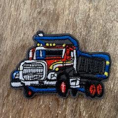 Embroidered dump truck iron-on patch on wood table