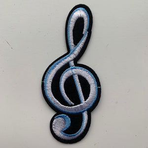 Large black and white embroidered treble clef iron-on patch in white, blue, and black, measuring 3.7 inches x 1.6 inches. Displayed on a white surface.