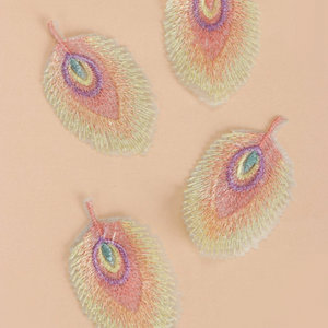 four Pastel feather iron-on embroidered patches displayed on a peach background