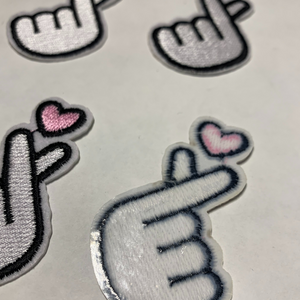 Four white embroidered Korean finger heart patches with pink hearts 