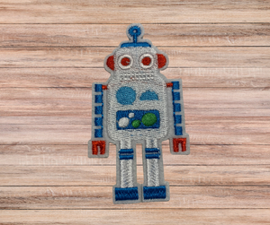 silver 3" embroidered polyester, blue, green, white and red robot iron patch on a wooden table