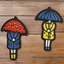 Load image into Gallery viewer, girl in raincoat under umbrella patch set. Red, blue, yellow embroidered PNW Seattle Rain Iron on patch set on wood table.
